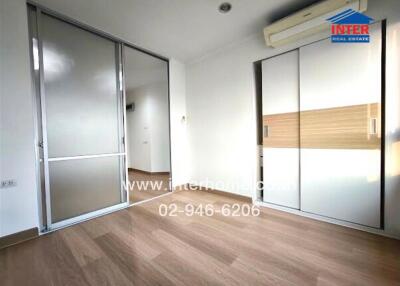 Spacious bedroom with wooden flooring, sliding doors, air conditioning, and built-in wardrobe