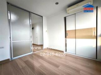 Spacious bedroom with wooden flooring, sliding doors, air conditioning, and built-in wardrobe