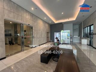 Modern building lobby with seating area, vending machines, and glass doors