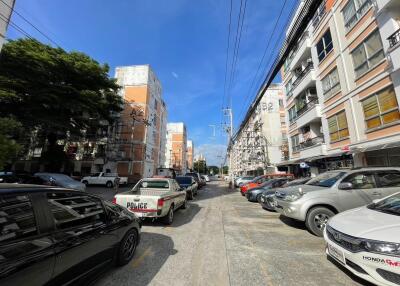 Street view of a residential area with parked cars and apartment buildings