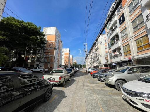 Street view of a residential area with parked cars and apartment buildings