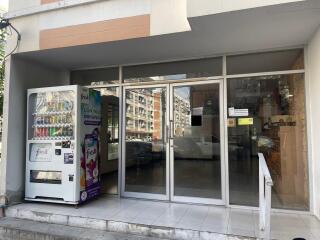 Entrance of an apartment building with a glass facade and a vending machine