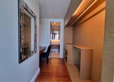 Modern bedroom with wooden flooring, a mirror, and built-in shelving