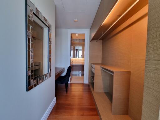 Modern bedroom with wooden flooring, a mirror, and built-in shelving