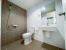 Modern bathroom with white sink, toilet, and shower area