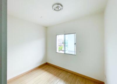 Empty bedroom with a window and wooden flooring