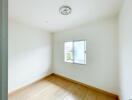 Empty bedroom with a window and wooden flooring