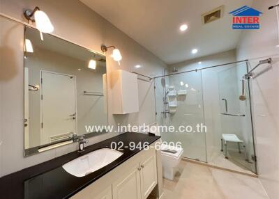 Well-lit modern bathroom with large mirror and glass shower enclosure
