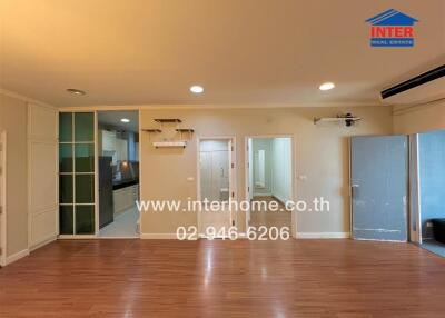 Spacious living area with wooden floor, glass doors, and access to adjacent rooms