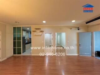 Spacious living area with wooden floor, glass doors, and access to adjacent rooms