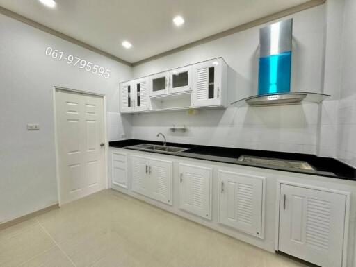 Modern kitchen with white cabinets, sink, and stainless steel hood