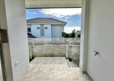 Outdoor view of a building with a partially visible house and tiled walkway