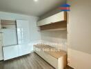 Minimalist living room with wooden floor, white cabinetry, and floating shelves