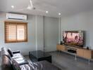 Modern living room with leather sofas, a wall-mounted TV, and air conditioning