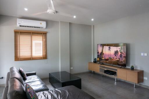 Modern living room with leather sofas, a wall-mounted TV, and air conditioning