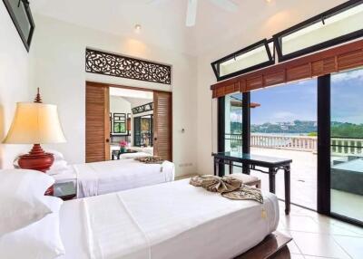 Spacious bedroom with twin beds, large windows, and balcony access