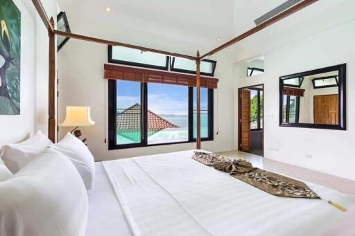 Bright spacious bedroom with a canopy bed and ocean view