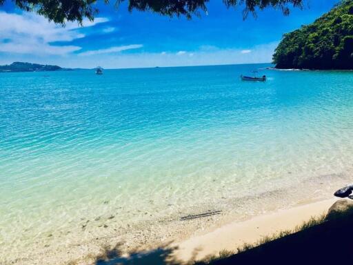 Scenic beach view with clear blue water and a boat in the distance