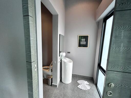 Modern bathroom with pedestal sink and separate toilet area