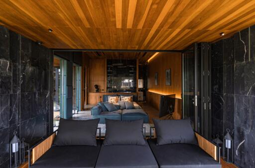 Modern living area with wooden ceiling and black marble walls