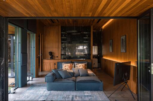 Modern living room with a wooden ceiling, large sofa, and a television.