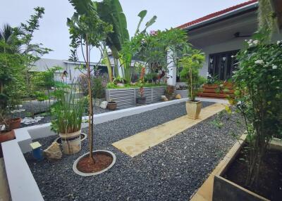 Beautifully landscaped garden with various plants and trees, pathway, and outdoor sitting area