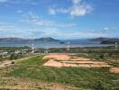 Scenic view of open land with hills and water in the background