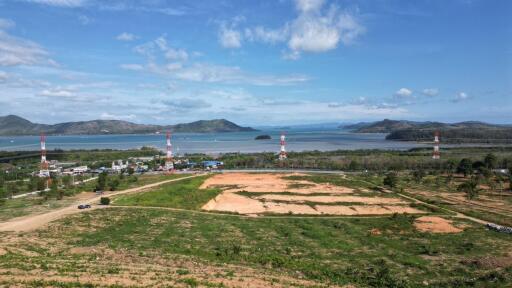 Scenic view of undeveloped land with radio towers and a distant view of water and mountains