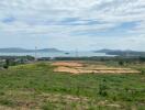 Scenic view of open land with a backdrop of water and mountains