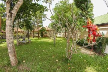 Spacious well-maintained garden with trees and a small decorative shrine