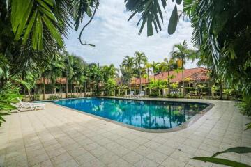 Outdoor swimming pool area with surrounding palm trees and a tiled deck.