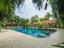 Outdoor swimming pool area with surrounding palm trees and a tiled deck.