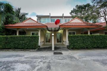 Exterior view of a residential building with green hedges and a satellite dish