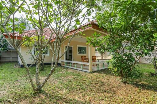 Exterior view of a house with a veranda surrounded by greenery