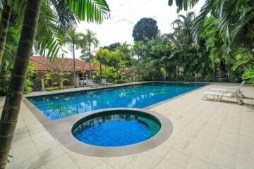 Swimming pool area with surrounding greenery and lounge chairs