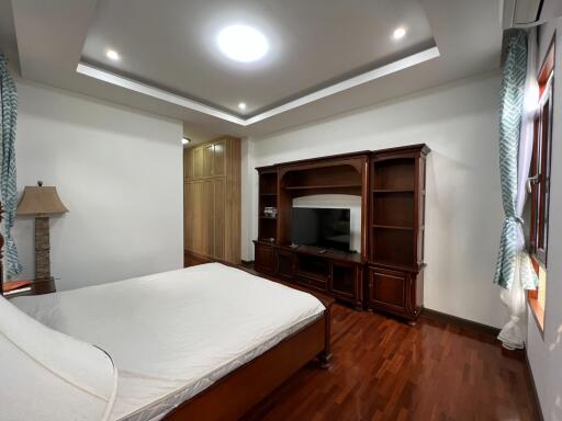 Spacious bedroom with wooden flooring and modern lighting