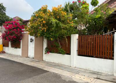 Exterior view of a house with a wooden fence and colorful flowering trees