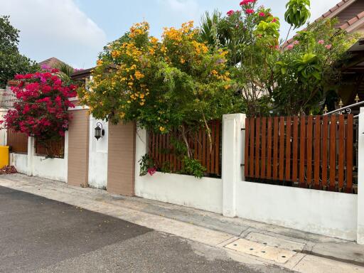 Exterior view of a house with a wooden fence and colorful flowering trees