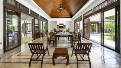 Spacious and well-lit living area with wooden ceiling and open glass doors