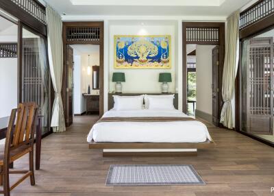 Spacious bedroom with a modern and luxurious design, featuring large windows, wooden furniture, and a decorative painting above the bed