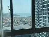 View from the window of a building showing a cityscape and the sea in the background