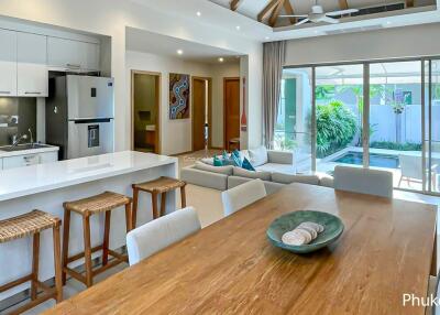 Modern open-plan living area with kitchen, dining table, and view of the pool