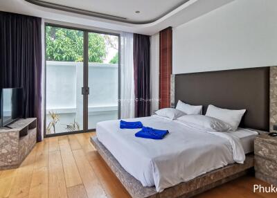 Modern bedroom with a large bed, wooden floor, and a TV