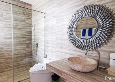 Modern bathroom with a walk-in shower, round mirror, and vessel sink