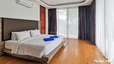 Modern bedroom with large windows and wooden flooring