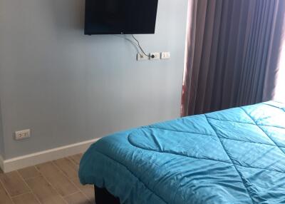 Bedroom with wall-mounted TV and blue bedspread