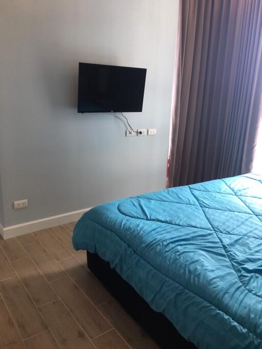 Bedroom with wall-mounted TV and blue bedspread