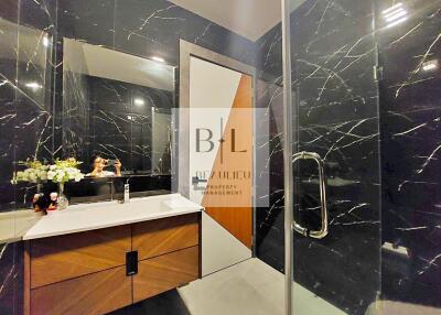 Modern bathroom with black marble walls and a glass-enclosed shower