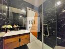 Modern bathroom with black marble walls and a glass-enclosed shower