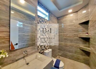 Modern bathroom with marble tiles, big mirror, and built-in shelves